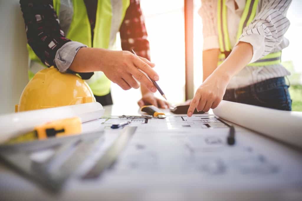 Construction professionals reviewing blueprints and plans on site.