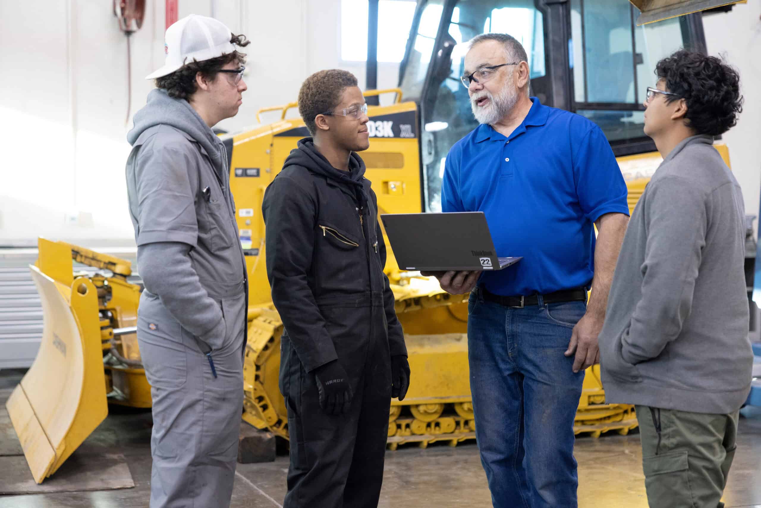 Instructor explaining machinery safety to students in a workshop.