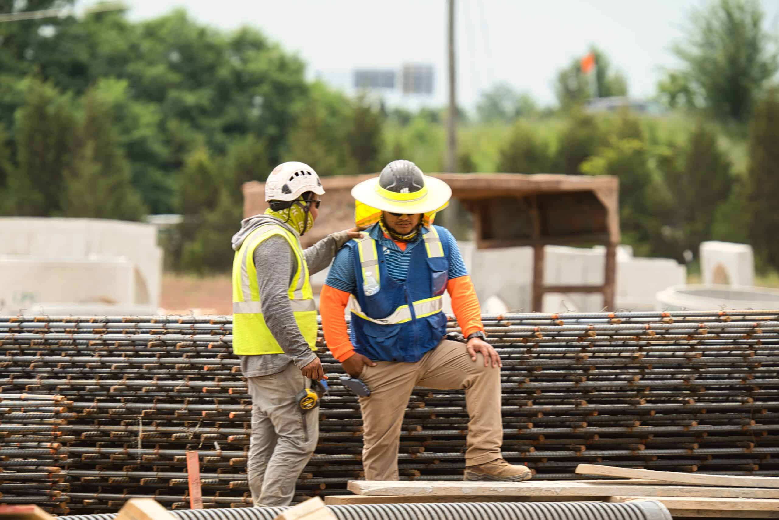 Construction workers discussing safety on a building site with rebar.