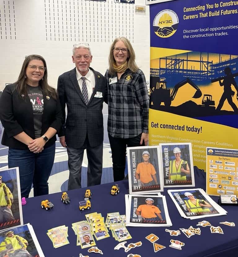 Three professionals at NV3C Network career event with construction-themed display.