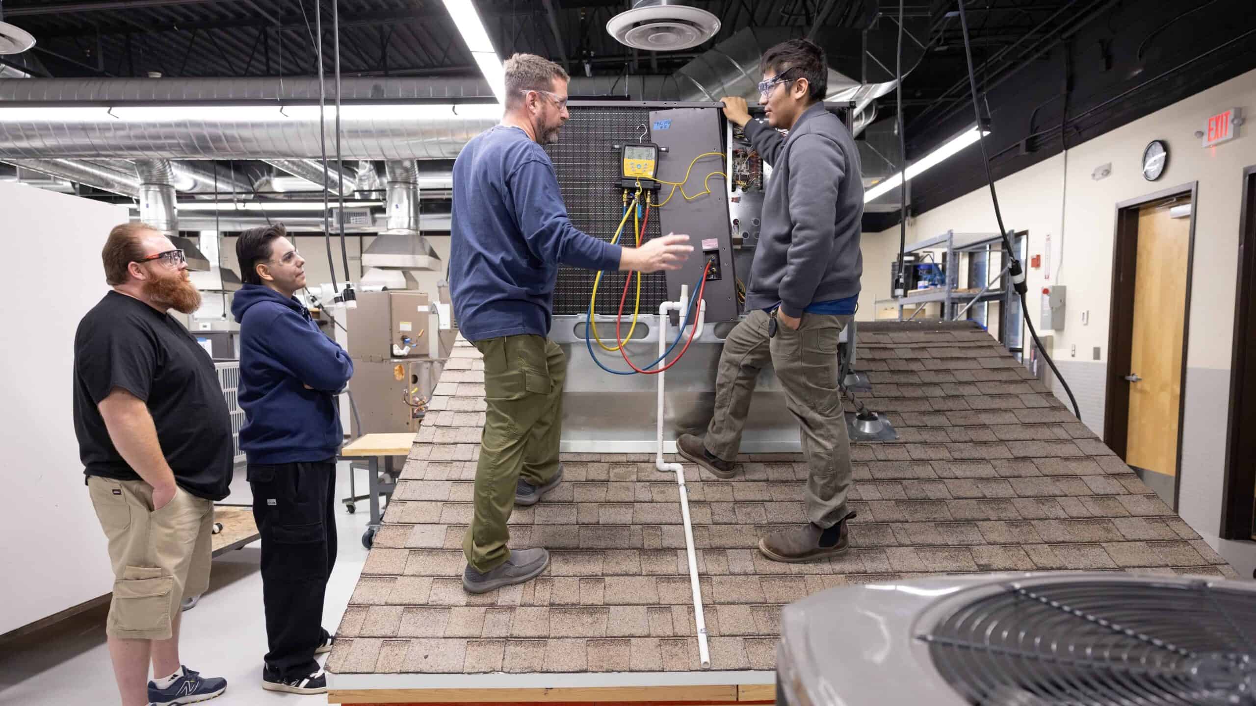 Team of engineers inspecting rooftop HVAC system in industrial setting.