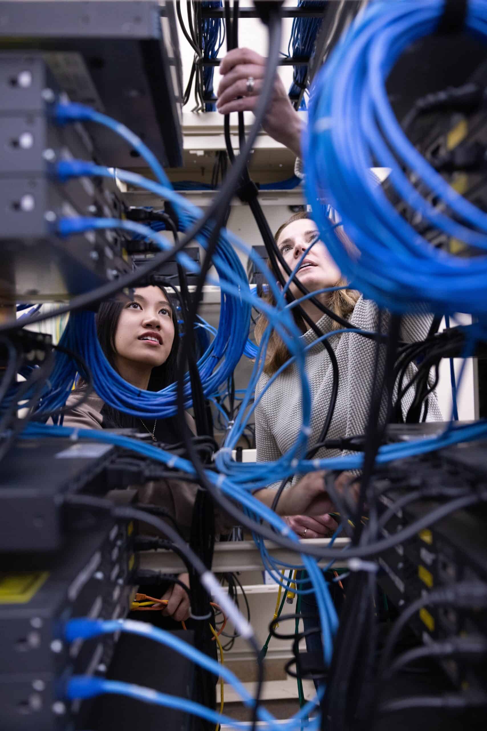 Technicians working on network cables in a server room.