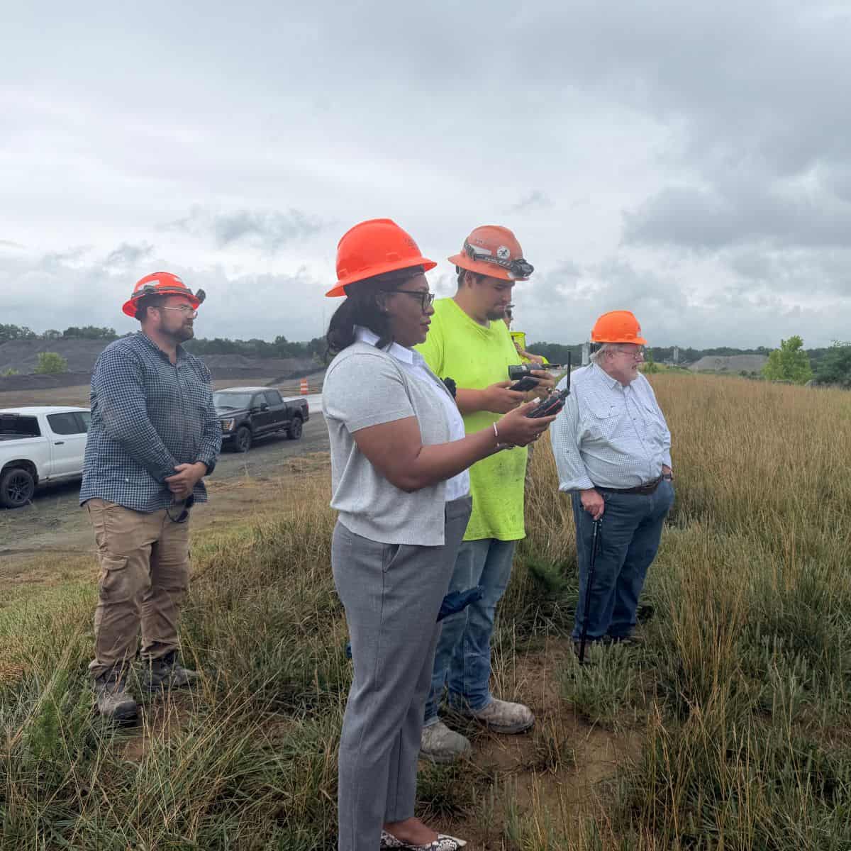 Group of engineers inspecting field with safety helmets and equipment.