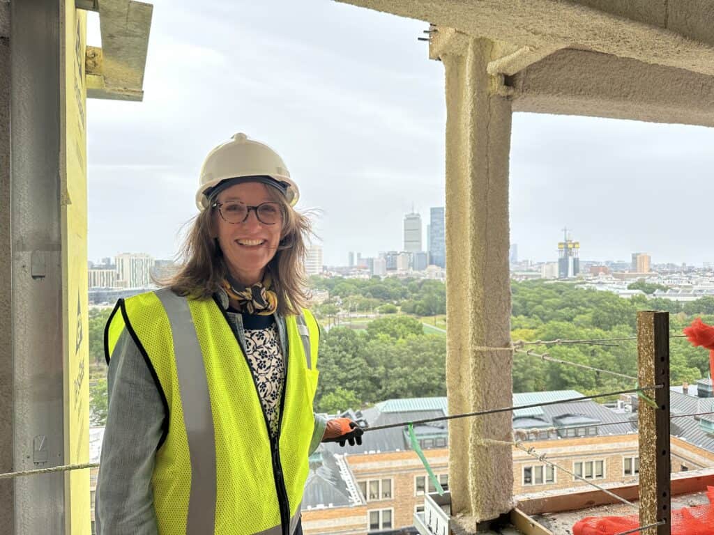 Construction worker woman in safety gear on high-rise building site.